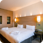 Chambre d'hôtel propre et bien rangée avec un lit et des tables de chevet.
